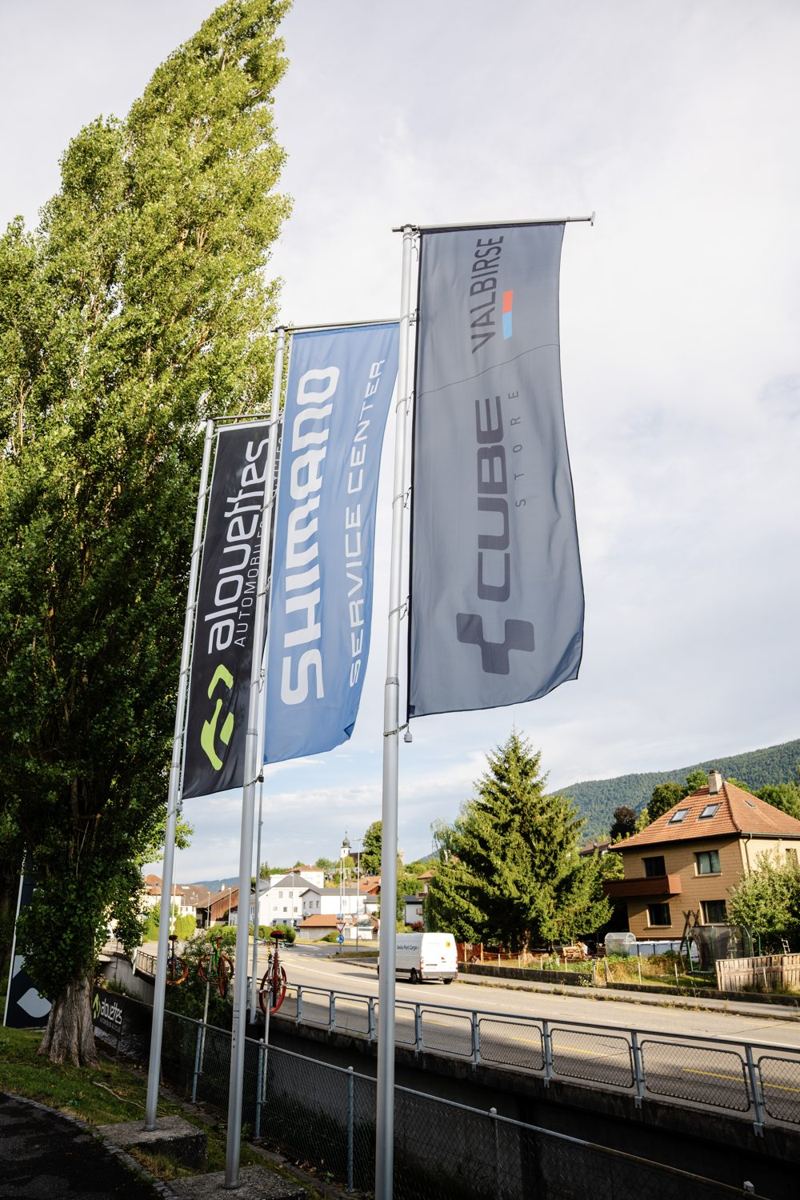 Alouette Cycles Fahnen vor der Bergkulisse des Berner Jura