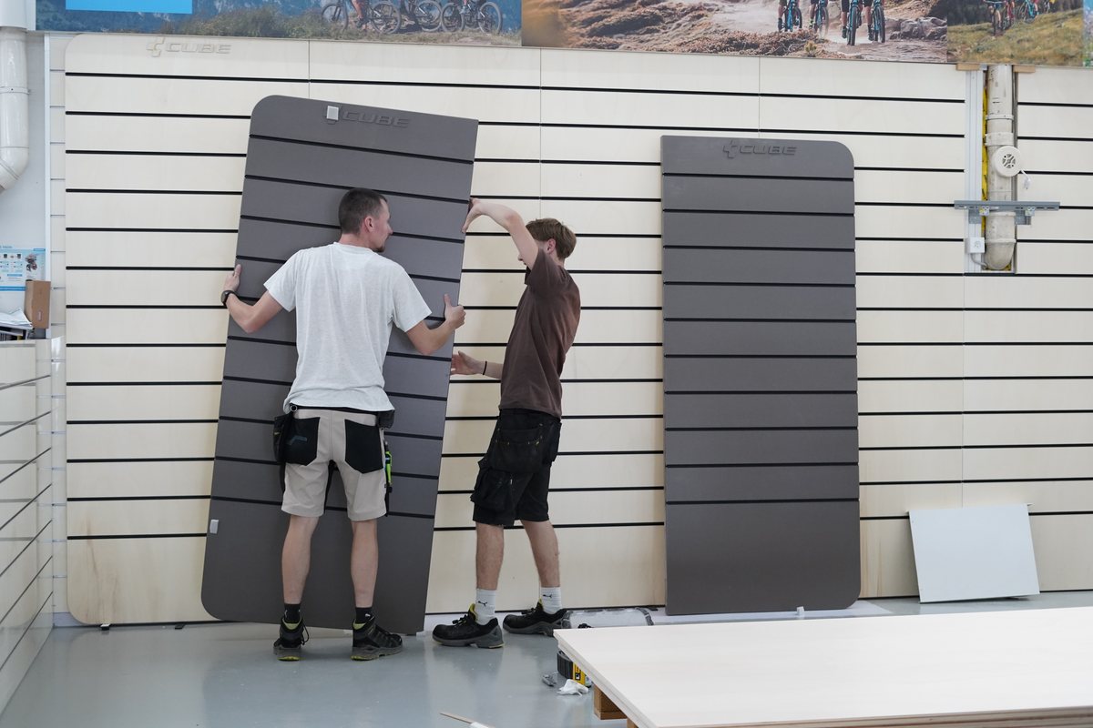 Deux artisans montent un élément mural dans le CUBE Store Valbirse